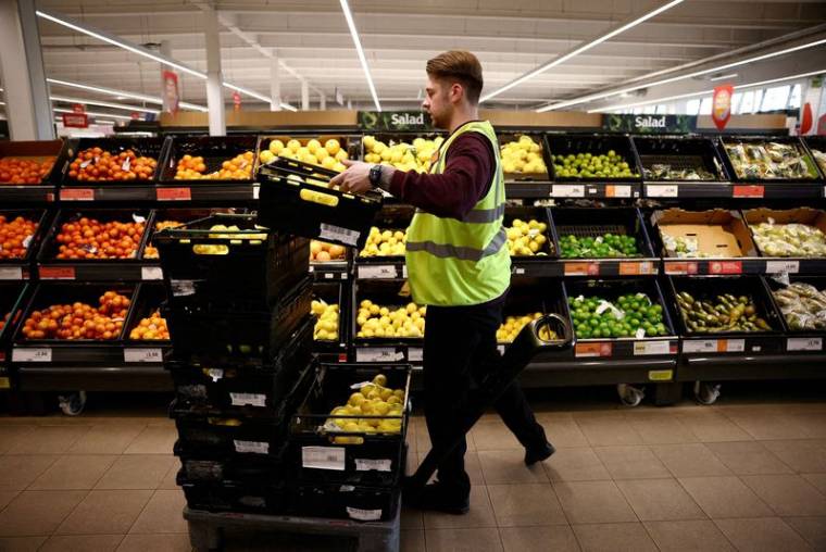 Un employé organise des produits dans un supermarché à Richmond, Londres