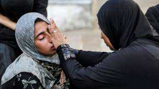 Une Palestinienne en réconforte une autre devant l'hôpital des Martyrs d'Aqsa à Deir el-Balah, dans le centre de la bande de Gaza, le 14 juin 2024 ( AFP / Bashar TALEB )
