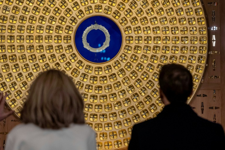 Brigitte et Emmanuel Macron regardent la couronne d'épines et le reliquaire conçus par l'artiste français Sylvain Dubuisson lors de leur visite à la cathédrale Notre-Dame de Paris, le 29 novembre 2024 ( POOL / Christophe PETIT TESSON )