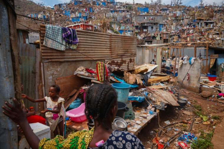 De jeunes habitantes du bidonville de Kawéni à Mamoudzou au milieu des décombres après le passage du cyclone Chido, le 20 décembre 2024 ( AFP / DIMITAR DILKOFF )