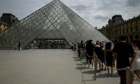 Des visiteurs font la queue devant la pyramide de l'architecteIeoh Ming Pei au musée du Louvre à Paris, le 11 juillet 2024 ( AFP / EMMANUEL DUNAND )