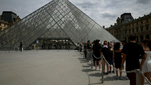 Des visiteurs font la queue devant la pyramide de l'architecteIeoh Ming Pei au musée du Louvre à Paris, le 11 juillet 2024 ( AFP / EMMANUEL DUNAND )