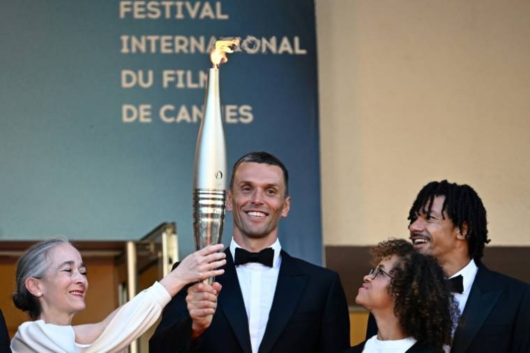 L'athlète paralympique Alexis Hanquinquant (c),  tient la flamme olympique avant la projection du film "Marcello Mio" au 77e Festival de Cannes, le 21 mai 2024 ( AFP / LOIC VENANCE )