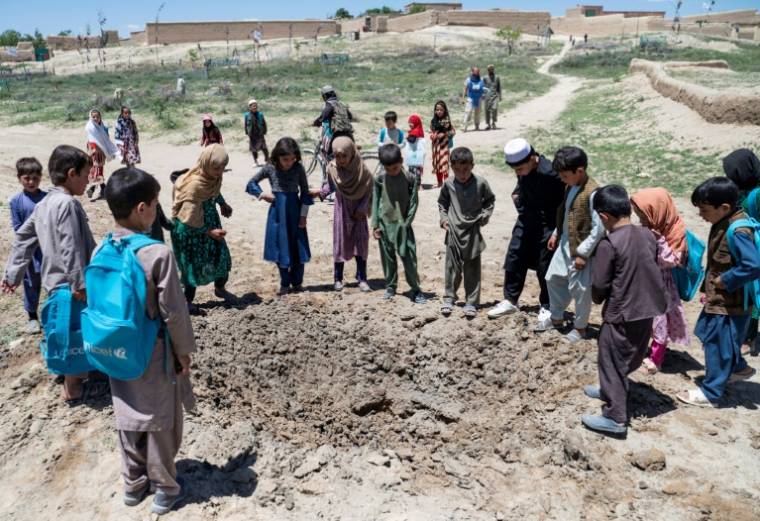Des enfants rassemblés autour d'un cratère après l'explosion d'une mine antichar pès du village de Qach Qala, dans la province de Ghazni, en Afghanistan ( AFP / Wakil KOHSAR )