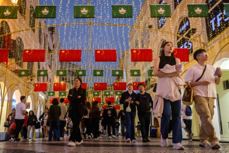 Des piétons passent sous des drapeaux de Macao et de la Chine sur la place Leal Senado à Macao, le 13 décembre 2024 ( AFP / Eduardo Leal )