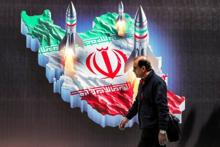 Un homme marche devant la carte de l'Iran dans le centre de Téhéran, le 15 avril 2024 ( AFP / ATTA KENARE )