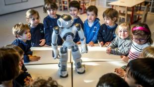 Des élèves de maternelle interagissent avec le robot éducatif et interactif Nao dans un établissement sur le campus universitaire de l'École polytechnique fédérale de Lausanne, en Suisse, le 23 février 2024 ( AFP / Fabrice COFFRINI )