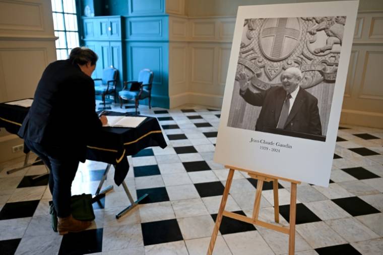 Une personne signe un livre de condoléances près du portrait de l'ancien maire Jean-Claude Gaudin décédé, le 20 mai 2024 à la mairie de Marseille ( AFP / Nicolas TUCAT )