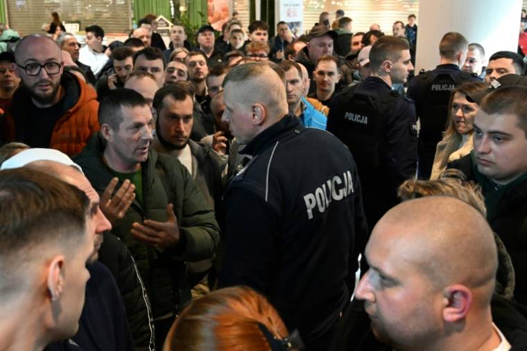 Des policiers polonais s'entretiennent avec des Ukrainiens rassemblés devant un bureau de délivrance de passeports ukrainiens fermé à Varsovie, le 24 avril 2024 ( AFP / Sergei GAPON )
