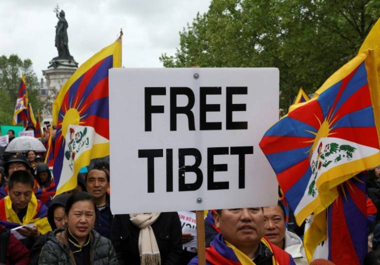 Des manifestants portent des drapeaux tibétains et tiennent un panneau "Tibet Libre" lors d'un rassemblement contre la venue en France du président chinois Xi Jinping, le 5 mai 2024 à Paris   ( AFP / Geoffroy VAN DER HASSELT )
