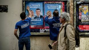 Des bénévoles du RN collent des affiches de campagne de Jordan Bardella, président du parti et tête de liste aux européennes, le 6 mai 2024 à Lyon ( AFP / JEFF PACHOUD )