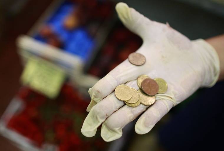 Un vendeur tient des pièces d'euros sur un marché du centre de Rome