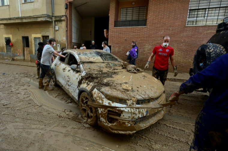 Des habitants tentent de bouger une voiture dans la ville de Massanassa, dans la région de Valence, le 8 novembre 2024 ( AFP / JOSE JORDAN   )