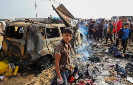 Des personnes se rassemblent sur le site d'une frappe nocturne ayant mis le feu à des tentes occupées par des Palestiniens déplacés dans un camp à Rafah, dans la bande de Gaza, le 27 mai 2024 ( AFP / Eyad BABA )