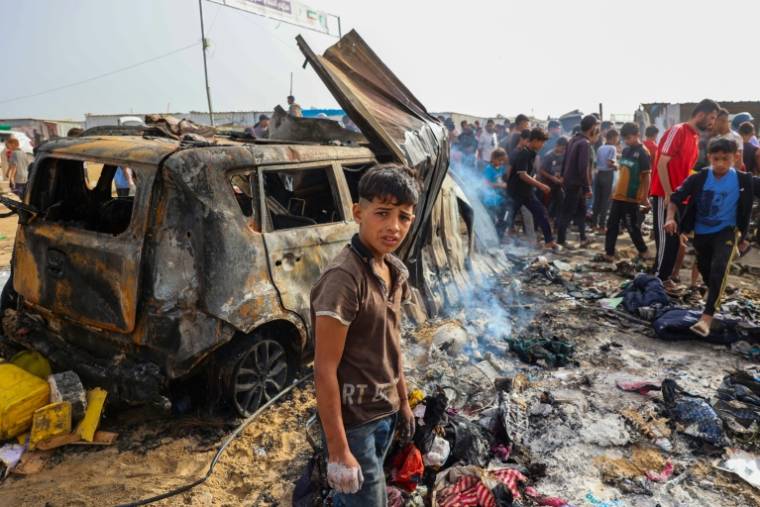 Des personnes se rassemblent sur le site d'une frappe nocturne ayant mis le feu à des tentes occupées par des Palestiniens déplacés dans un camp à Rafah, dans la bande de Gaza, le 27 mai 2024 ( AFP / Eyad BABA )