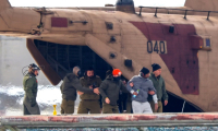 L'otage libéré Avera Mengistu (2e D), accompagné de forces israéliennes, débarque d'un hélicoptère militaire sur l'héliport du centre hospitalier Sourasky-Ichilov à Tel-Aviv, le 22 février 2025 ( AFP / Jack Guez )