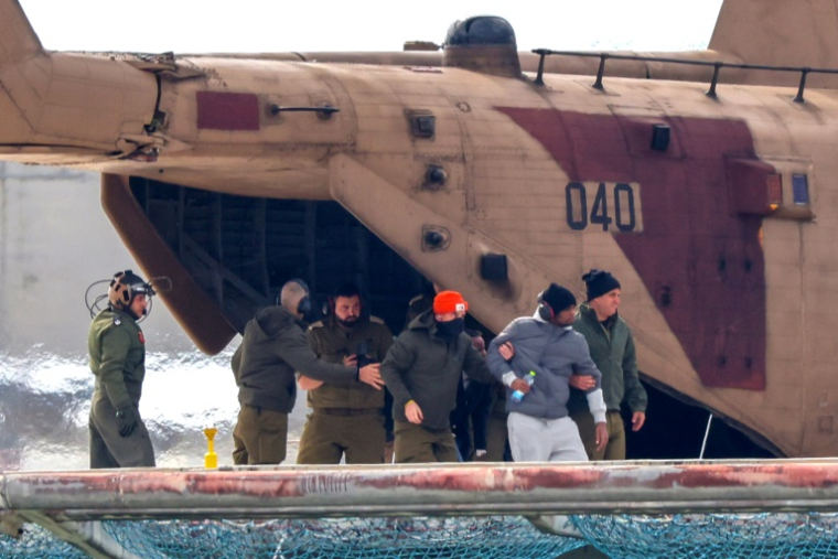 L'otage libéré Avera Mengistu (2e D), accompagné de forces israéliennes, débarque d'un hélicoptère militaire sur l'héliport du centre hospitalier Sourasky-Ichilov à Tel-Aviv, le 22 février 2025 ( AFP / Jack Guez )