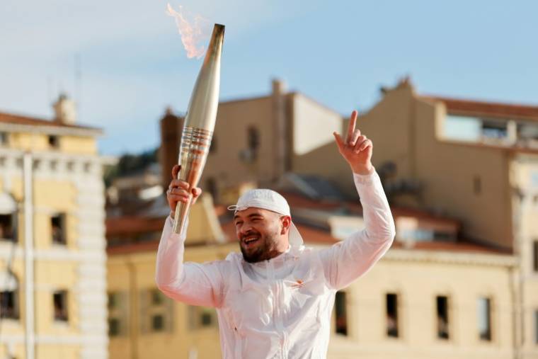 Le rappeur français Jul avec la torche olympique sur le Vieux Port, à Marseille, après avoir allumé le chaudron, le 8 mai 2024 ( POOL / Ludovic MARIN )