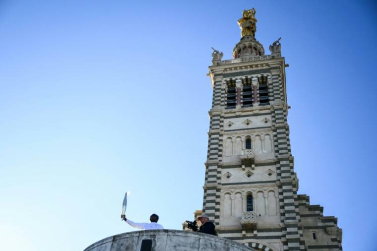 L'ancien footballeur Basile Boli tient la flamme olympique dans le cadre des relais de la flamme olympique et paralympique à la basilique Notre-Dame de la Garde, à Marseille, le 9 mai 2024 ( AFP / CHRISTOPHE SIMON )