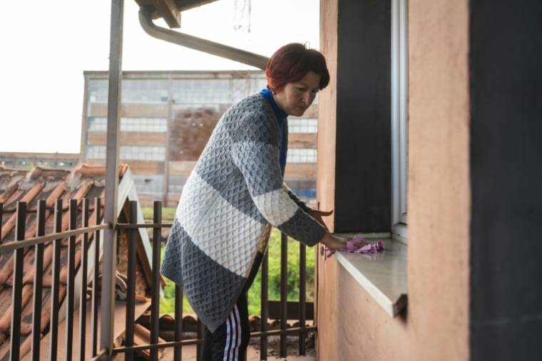 Dragana Milic nettoie une fenêtre de sa maison située près d'une aciérie exploitée par le groupe chinois HBIS, dans le village de Radinac, le 25 avril 2024 en Serbie ( AFP / Andrej ISAKOVIC )