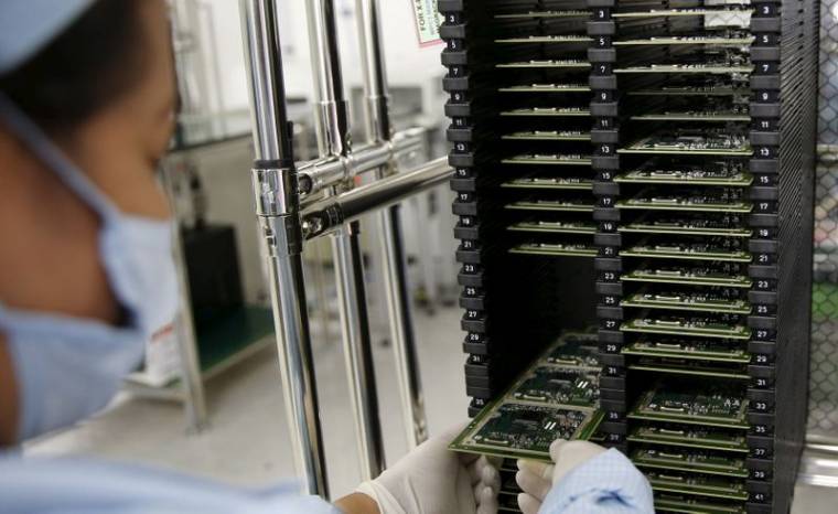 A worker of Ayala Corp's Integrated Micro-Electronics Inc. (IMI) removes computer chips from a shelve at an electronics assembly line in Binan, Laguna