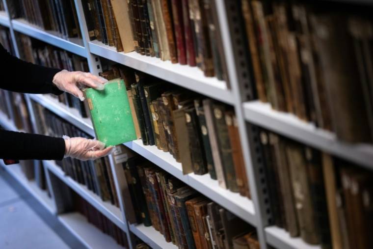 Aude Therstappen, conservatrice de la BNU (Bibliothèque nationale et universitaire) à Strasbourg, retire des réserves un livre coloré en vert avec l'arsenic, le 17 mai 2024 ( AFP / SEBASTIEN BOZON )
