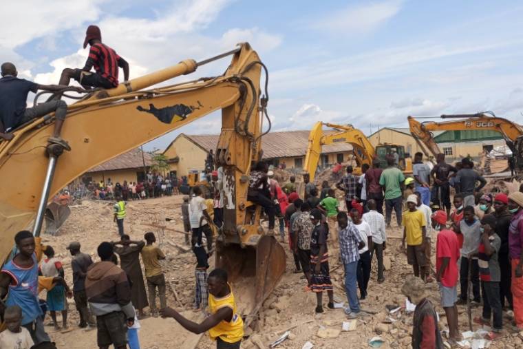 Des passants devant des pelleteuses près du site d'une école qui s'est effondrée à Jos, au Nigeria, le 12 juillet 2024 ( AFP / Muhammad Tanko Shittu )
