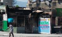 Une femme passe devant un un restaurant brûlé par des bandes armées, le 12 mars 2024 à Port-au-Prince, en Haïti ( AFP / Clarens SIFFROY )