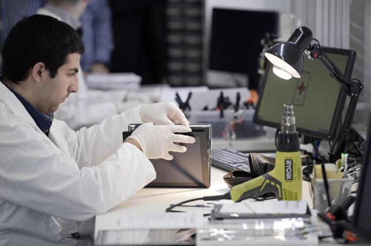 Un technicien répare une tablette  dans l'entreprise "Allo Smartphone" à Paris, le 7 novembre 2014. ( AFP / STEPHANE DE SAKUTIN )