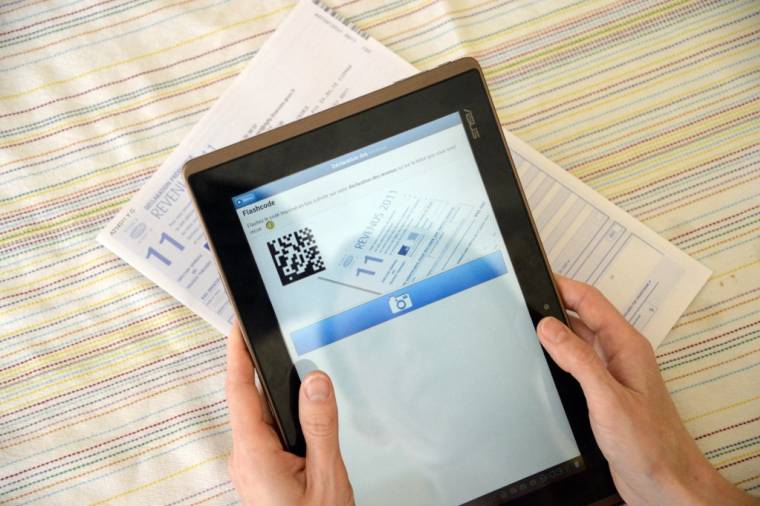 Une personne utilise une tablette près d'une déclaration papier des revenus de l'année 2012, le 27 avril 2012 à Cesson-Sevigné. ( AFP / DAMIEN MEYER )