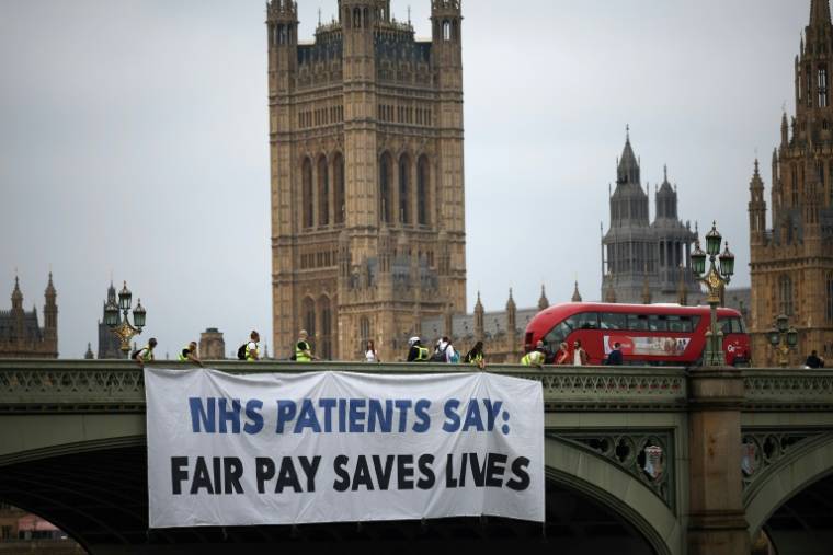 Une banderole sur le pont de Westminster pour soutenir la grève des jeunes médecins qui réclament de meilleurs salaires et conditions de travail, le 27 juin 2024 à Londres ( AFP / HENRY NICHOLLS )