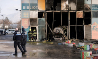 Des pompiers et des policiers devant une bibliothèque incendiée à Grenoble par une voiture-bélier en feu, le 19 février 2025 ( AFP / Maxime GRUSS )