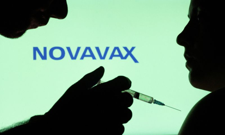 Des personnes posent avec une seringue devant le logo Novavax