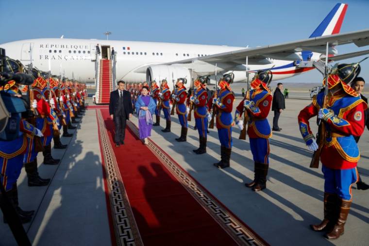 Le président français Emmanuel Macron accueilli par la ministre mongole des Affaires étrangères, Battsetseg Batmunkh (d), à son arrivée à l'aéroport d'Oulan-Bator, le 21 mai 2023 en Mongolie ( AFP / Ludovic MARIN )
