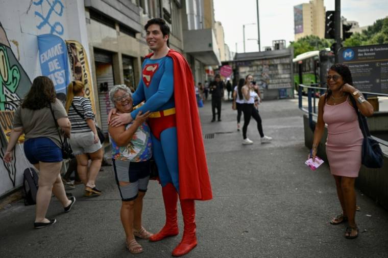 Leonardo Muylaert, le "Superman brésilien", avec une habitante du quartier de Tijuca, le 18 mars 2024 à Rio de Janeiro ( AFP / MAURO PIMENTEL )