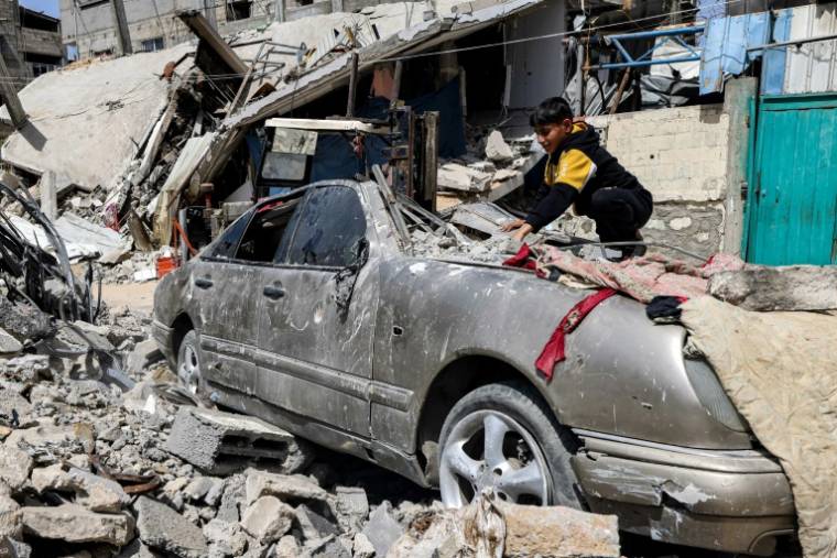 Un jeune Palestinien enlève d'un véhicule endommagé les décombres tombés d'un bâtiment détruit par une frappe israélienne à Rafah, dans le sud de la bande de Gaza, le 5 avril 2024 ( AFP / MOHAMMED ABED )