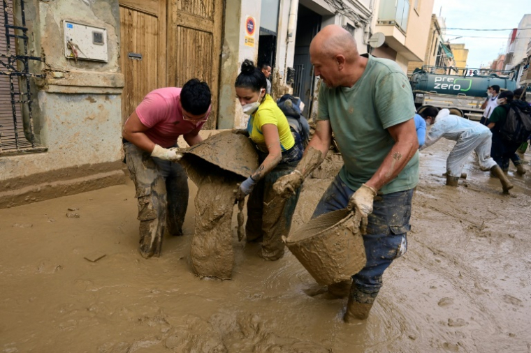 Des habitants nettoient leurs maisons  en évacuant la boue à Massanassa, dans la région de Valence (Espagne), le 8 novembre 2024  ( AFP / JOSE JORDAN   )