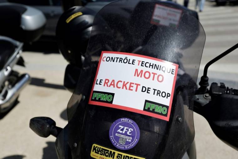 "Contrôle technique moto: le racket de trop", indique l'affiche déposée sur la moto d'un manifestant le 13 avril 2024 à Paris ( AFP / STEPHANE DE SAKUTIN )