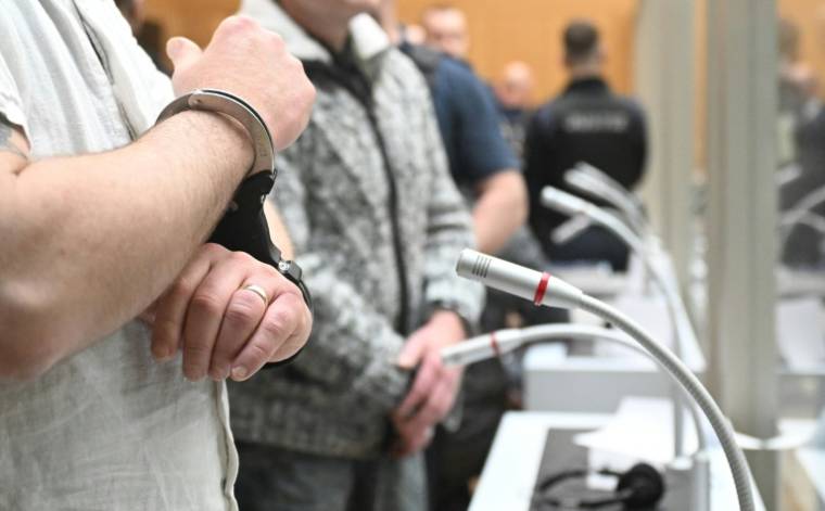 L'un des neuf suspects, menoté, arrive dans la salle d'audience du tribunal de Stuttgart (sud-ouest), pour le procès d'un réseau armé qui avait projeté un coup d'Etat en Allemagne, le 29 avril 2024 ( POOL / Bernd Weißbrod )