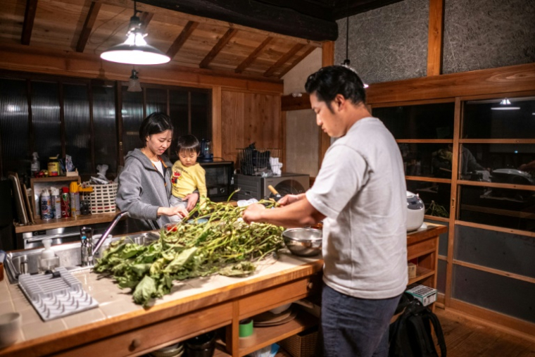 Rie (g) et Toshiki Kato, et leur fils Kuranosuke, dans la cuisine de leur maison du village d'Ichinono, le 20 octobre 2024 au Japon ( AFP / Philip FONG )