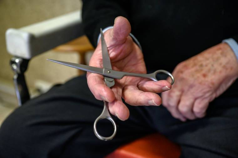 Le coiffeur Roger Amilhastre, âgé de 90 ans, tient une paire de ciseaux dans son salon à Saint-Girons, en Ariège, le 16 avril 2024  ( AFP / Ed JONES )