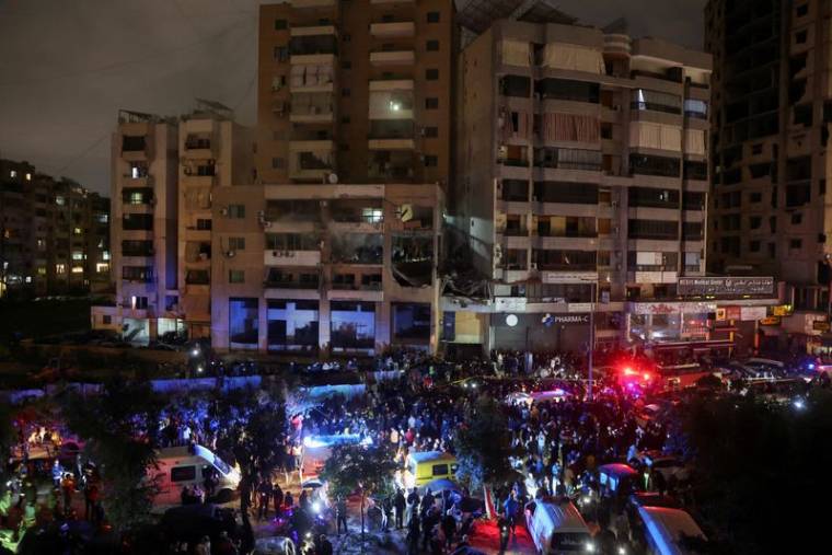 Photo des gens qui se rassemblent près d'un site endommagé suite à une explosion à Dahiyeh, dans la banlieue de Beyrouth