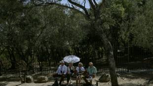 Des touristes sont assis à l'ombre près de l'Acropole à Athènes pendant une journée de canicule, le 12 juin 2024 ( AFP / STRINGER )