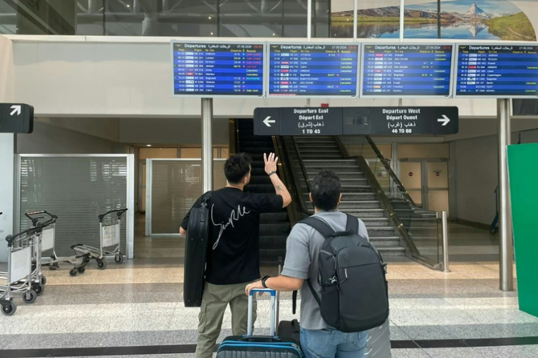 Des voyageurs consultent un tableau d'information sur les vols au départ de l'aéroport international de Beyrouth, le 27 septembre 2024 au Liban ( AFP / Sary CHMAYTELLI )