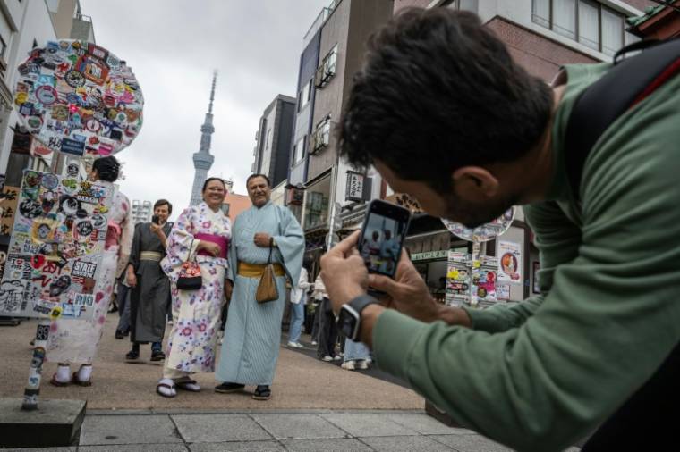 Des touristes en kimono se prennent en photo près du temple Sensoji à Tokyo le 30 Avril 2024 avec la tour de radiodiffusion Tokyo Skytree à l'arrière plan. Photo prise le 30 Avril 2024 ( AFP / Yuichi YAMAZAKI )