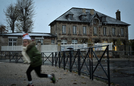 Un enfant passe devant une école sous la neige, à Luc-sur-Mer, dans le nord-ouest de la France, le 21 novembre 2024 ( AFP / LOU BENOIST )