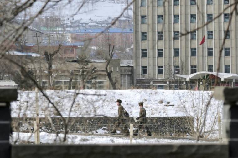 Deux soldats dans le village nord-coréen de Hyesan, vus depuis Changbai, dans la province de Jilin, au nord-est de la Chine, le 1er mars 2024 ( AFP / Pedro PARDO )