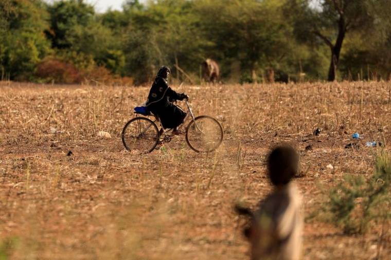 Photo d'archives: Un enfant qui a fui avec ses parents les attaques de militants armés dans la région du Sahel observe une femme à vélo dans un camp de personnes déplacées au Burkina Faso