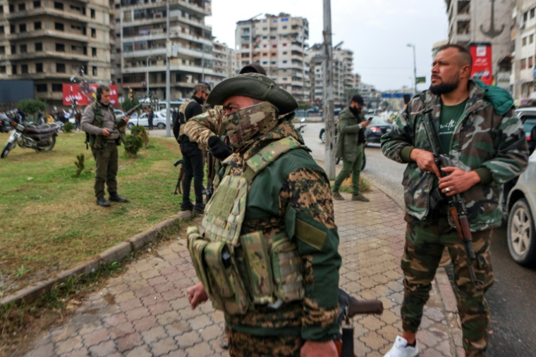 Des combattants affiliés à la nouvelle administration syrienne montent la garde dans les rues de la ville côtière de Lattaquié, dans l'ouest de la Syrie, le 26 décembre 2024 ( AFP / AAREF WATAD )