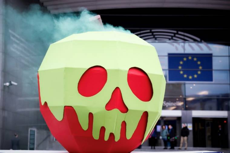 Une installation représentant "une pomme empoisonnée" lors d'une manifestation devant le Parlement européen, le 11 avril 2024 à Bruxelles ( AFP / Kenzo TRIBOUILLARD )